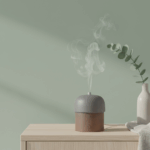 Minimalistischer Aromadiffusor verströmt Dampf auf Sideboard, Keramikvase und Leinentuch, weiches Studiolicht